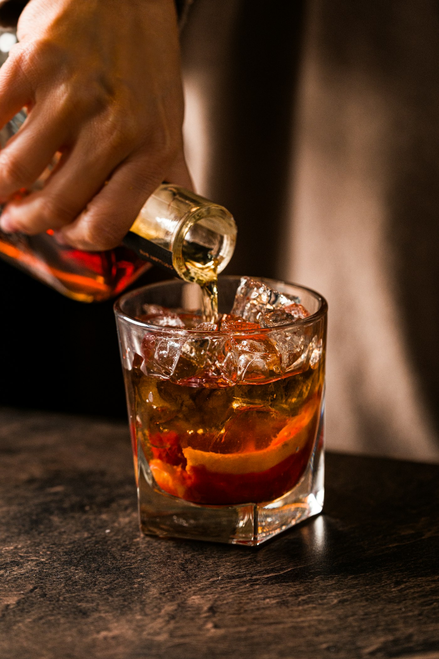 Barman versant un alcool ambré sur des glaçons