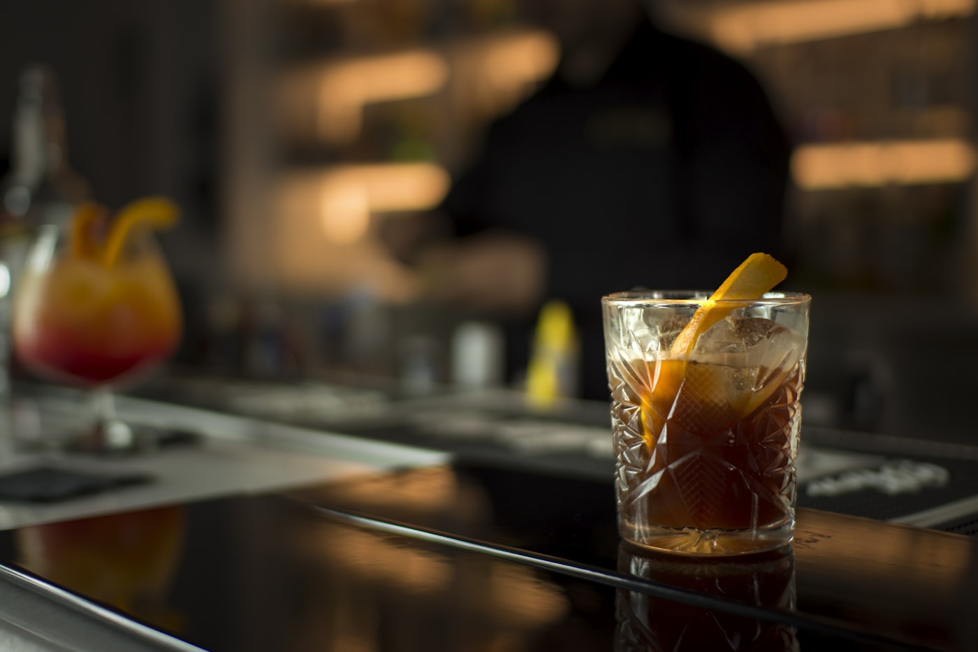 Cocktail avec zeste d'orange posé sur le comptoir
