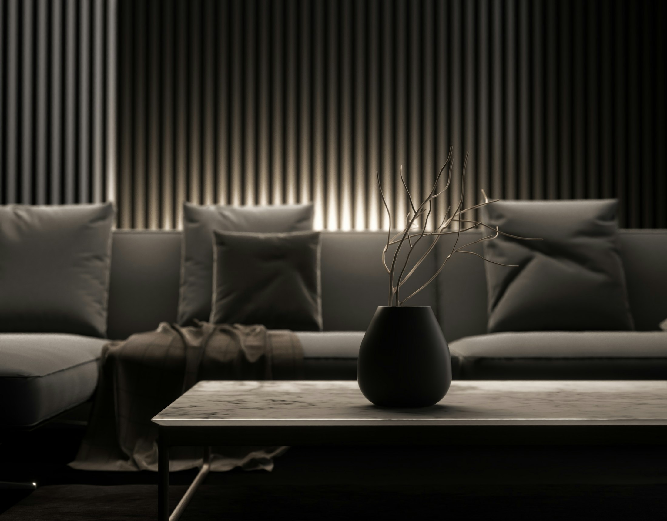 Salon sombre du lounge, canapé et table basse éclairés par une lumière rasante